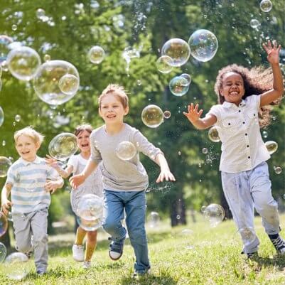 Children running and playing bubbles