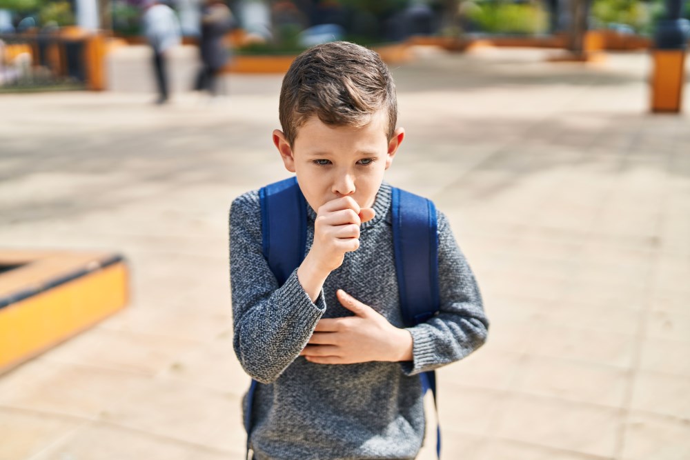 A child at school coughing while walking to class.