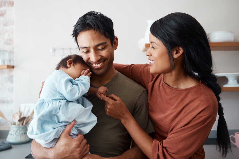 Parents holding their newborn child and smiling.