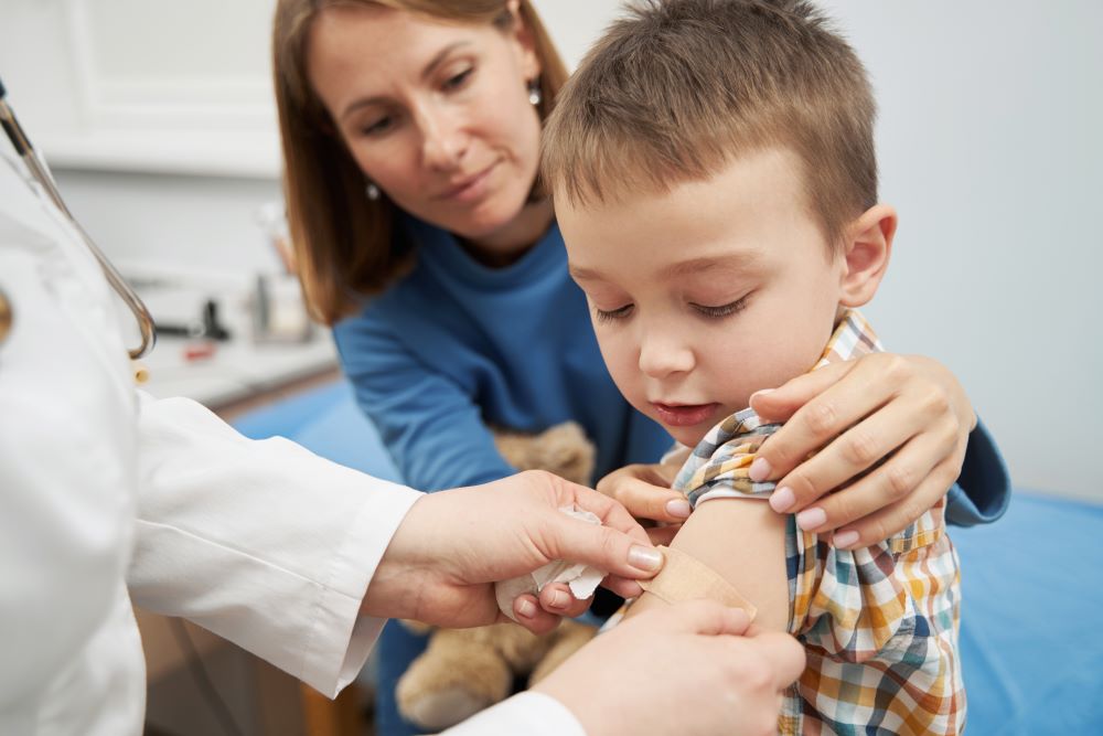 A pediatrician putting a band aid on a child's arm after a vaccination.