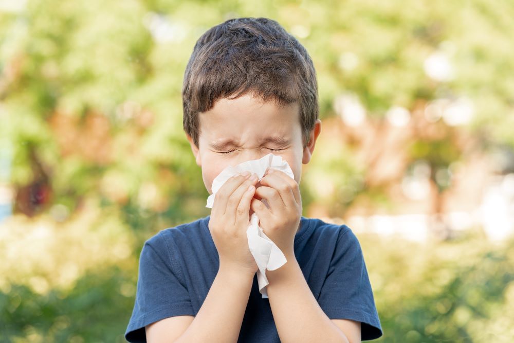 A young sick child blowing his nose during flu season.