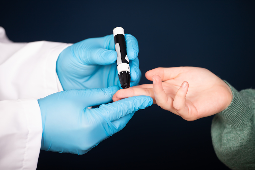 doctor pricking the finger of a child with type 1 diabetes