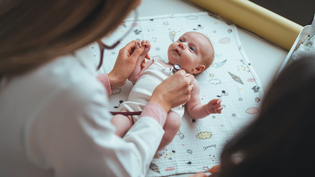 Pediatrician listening to newborn's lungs with stethoscope.