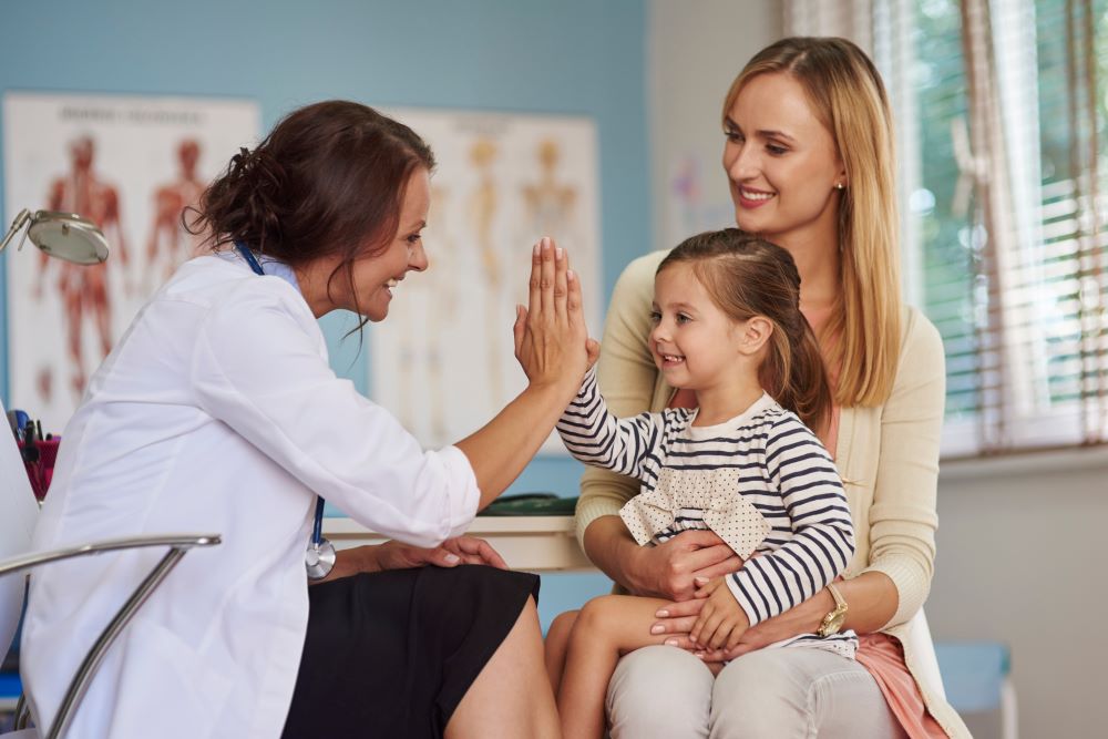 A woman pediatrician talking with a patient and her mother.