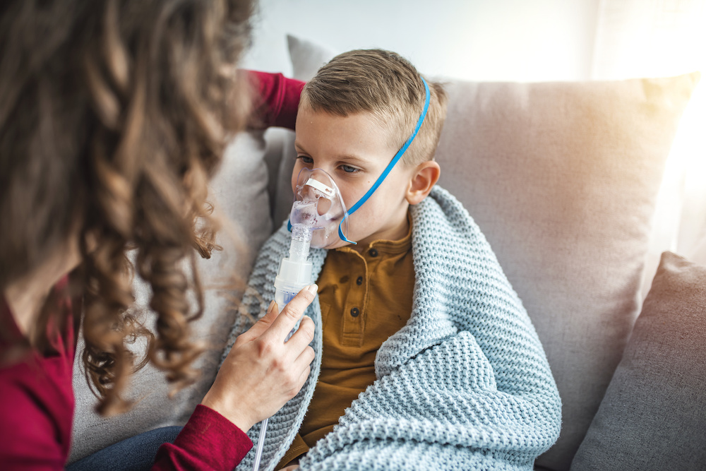 Woman with son doing inhalation with nebulizer at home. Pediatric Pulmonary doctor's visit has been scheduled.